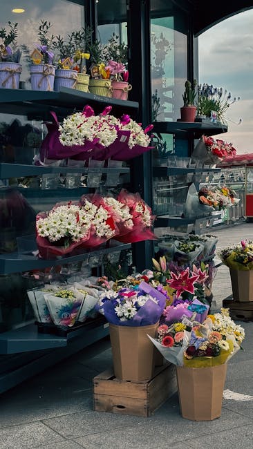 A display of fresh floral arrangements and bouquets at a flower shop on Seven Sisters Road South Tottenham, captured in daylight through a large glass window. The scene includes multiple bouquets wrap