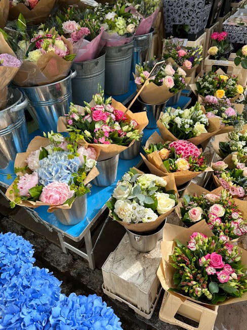 A vibrant display of floral arrangements at a flower stall, featuring bouquets composed of pink roses, white hydrangeas, and pastel-colored carnations wrapped in brown kraft paper, with some arranged 